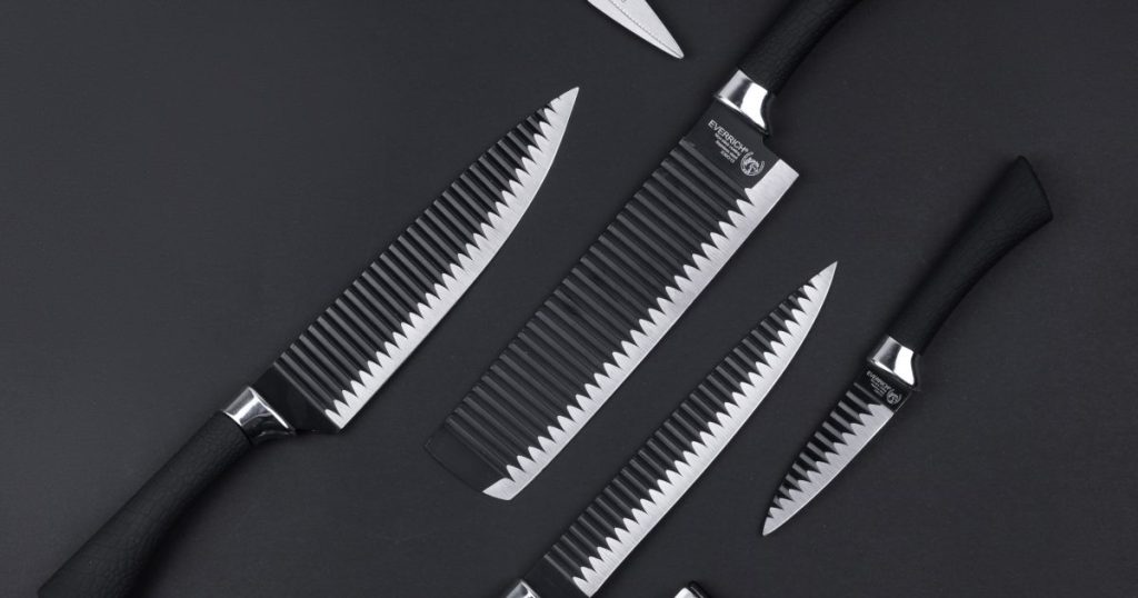 Assortment of kitchen knives arranged on a dark surface