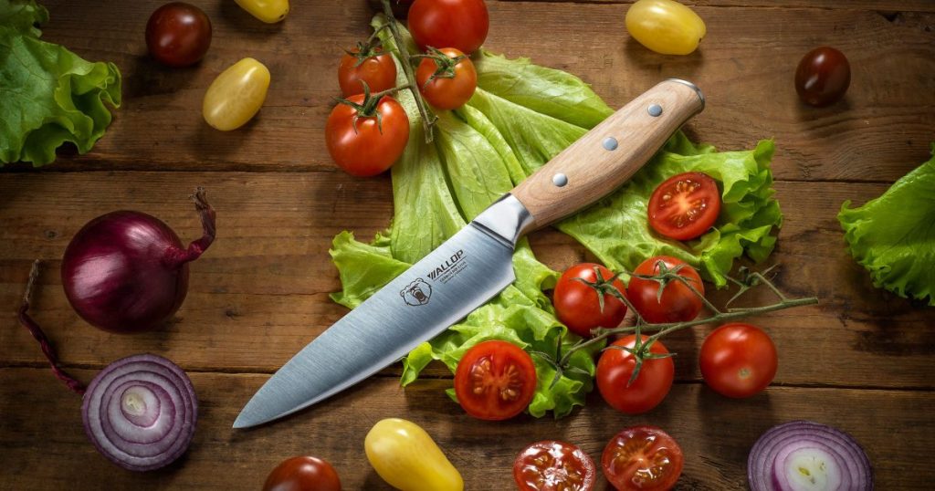 Kitchen knife with fresh vegetables on a wooden preparation surface