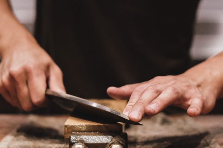 Person carefully sharpening a kitchen knife on a fixed abrasive stone